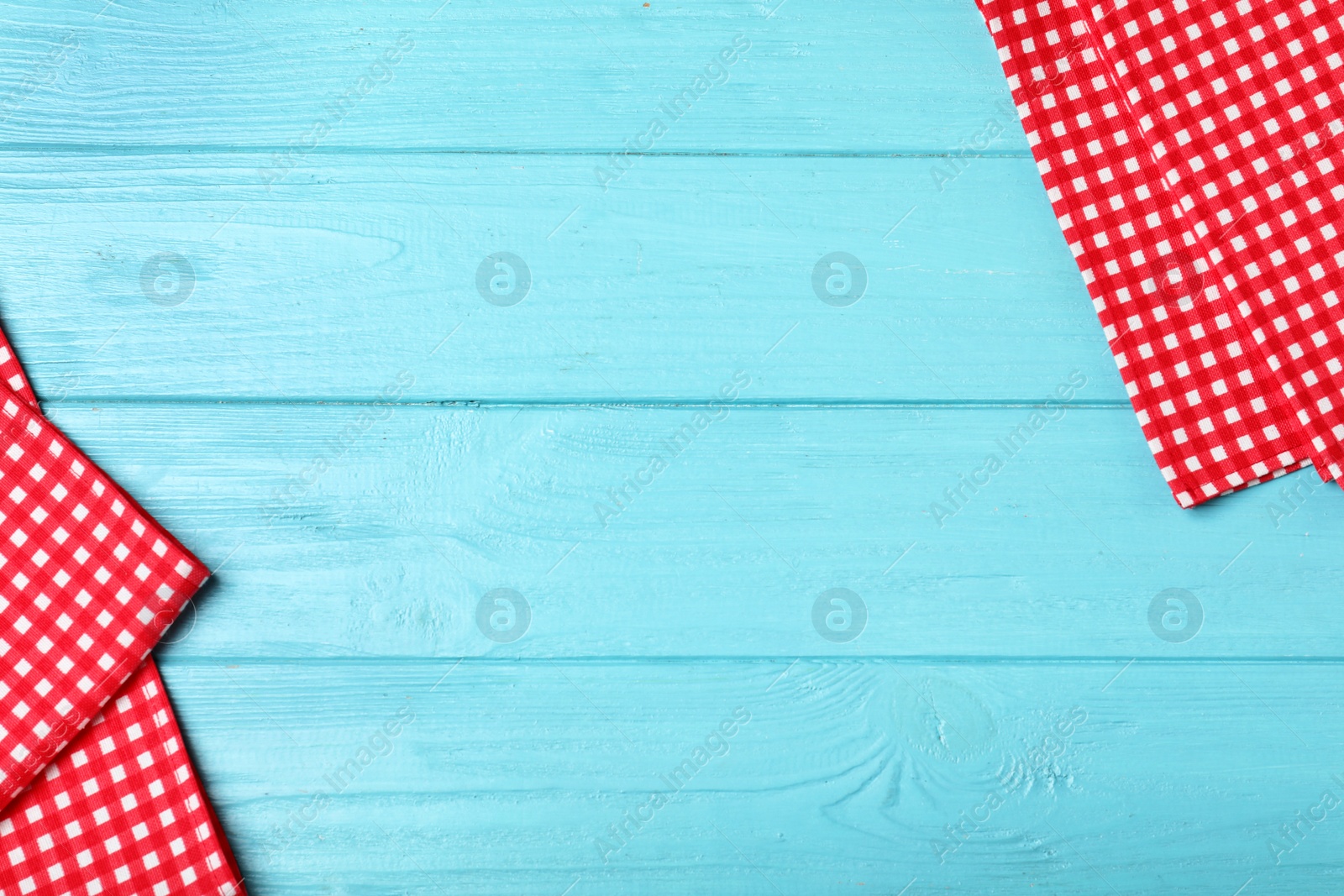 Photo of Checkered picnic napkins on color wooden background, top view. Space for text