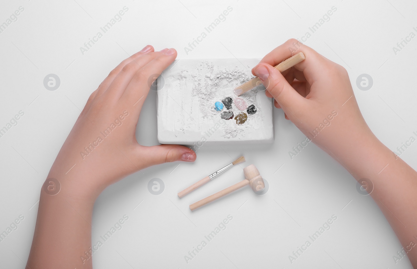 Photo of Child playing with Excavation kit on white background, top view. Educational toy for motor skills