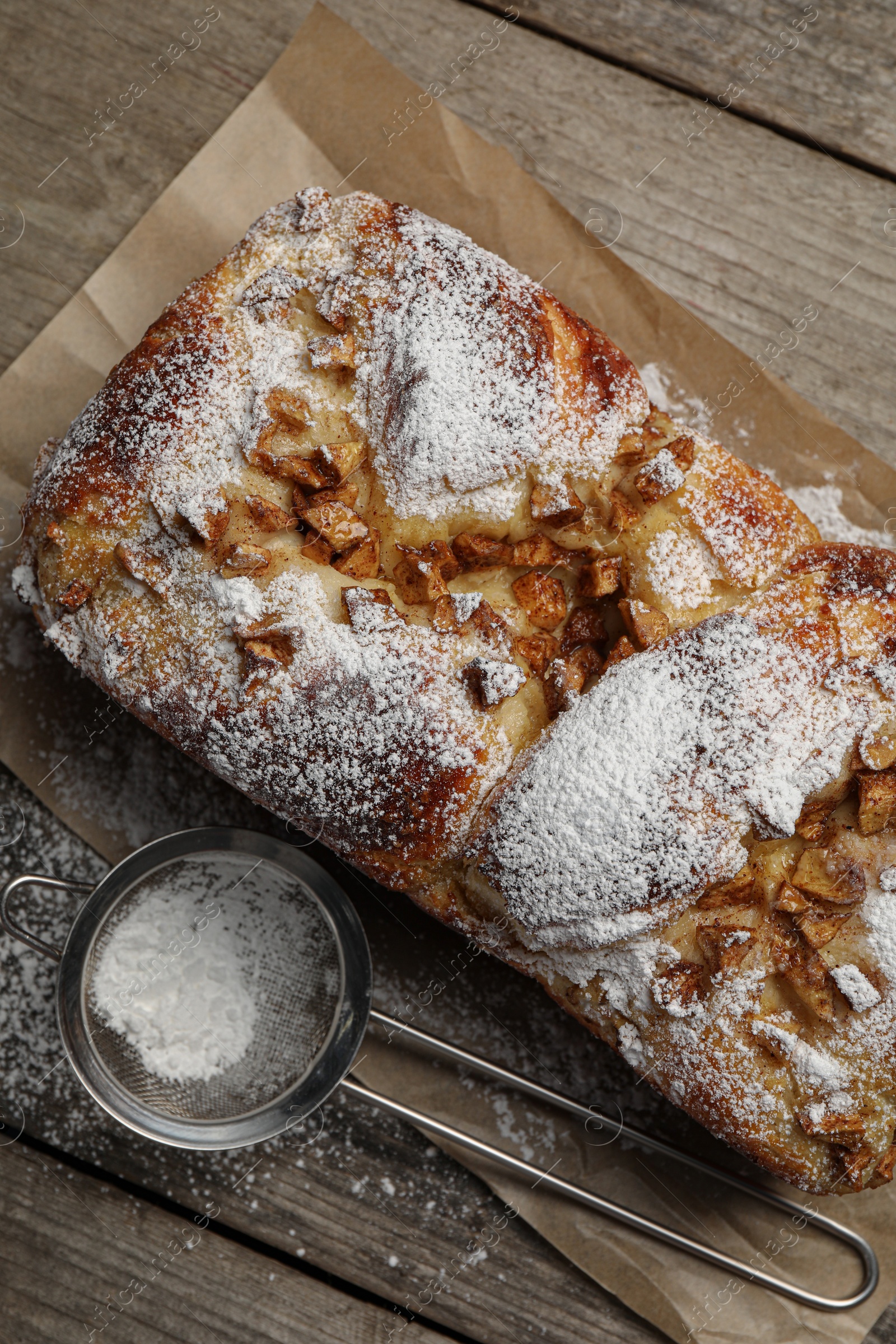 Photo of Delicious yeast dough cake and strainer with powdered sugar on wooden table, flat lay