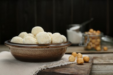 Photo of Delicious candies with coconut flakes and hazelnut on wooden table, space for text