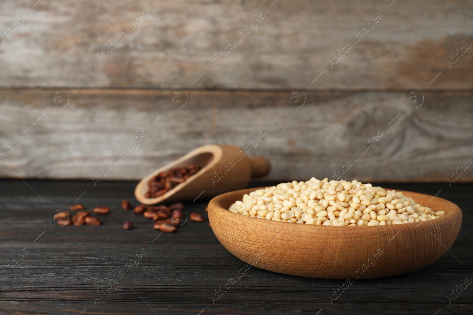 Photo of Dish with pine nuts on table against wooden background. Space for text