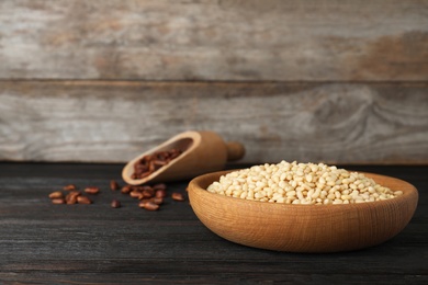 Photo of Dish with pine nuts on table against wooden background. Space for text