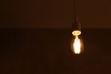 Photo of Lamp bulb on dark background. Space for text