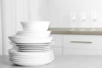 Photo of Stack of clean plates on grey table in kitchen. Space for text