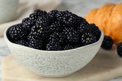 Bowl of fresh ripe blackberries on white marble table, closeup