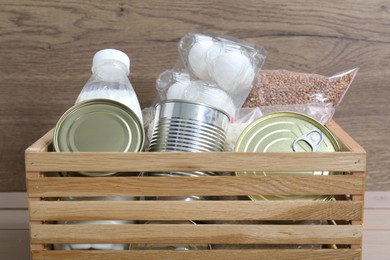Photo of Donation box with different food products on wooden table