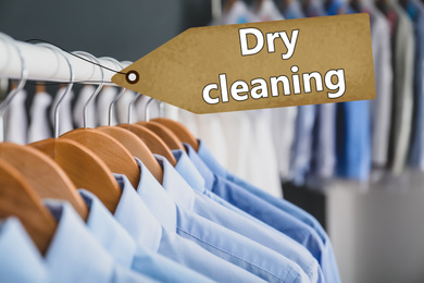 Rack with clean clothes on hangers after dry-cleaning indoors