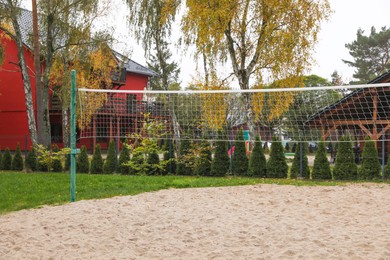 Sand volleyball court with net near trees and buildings