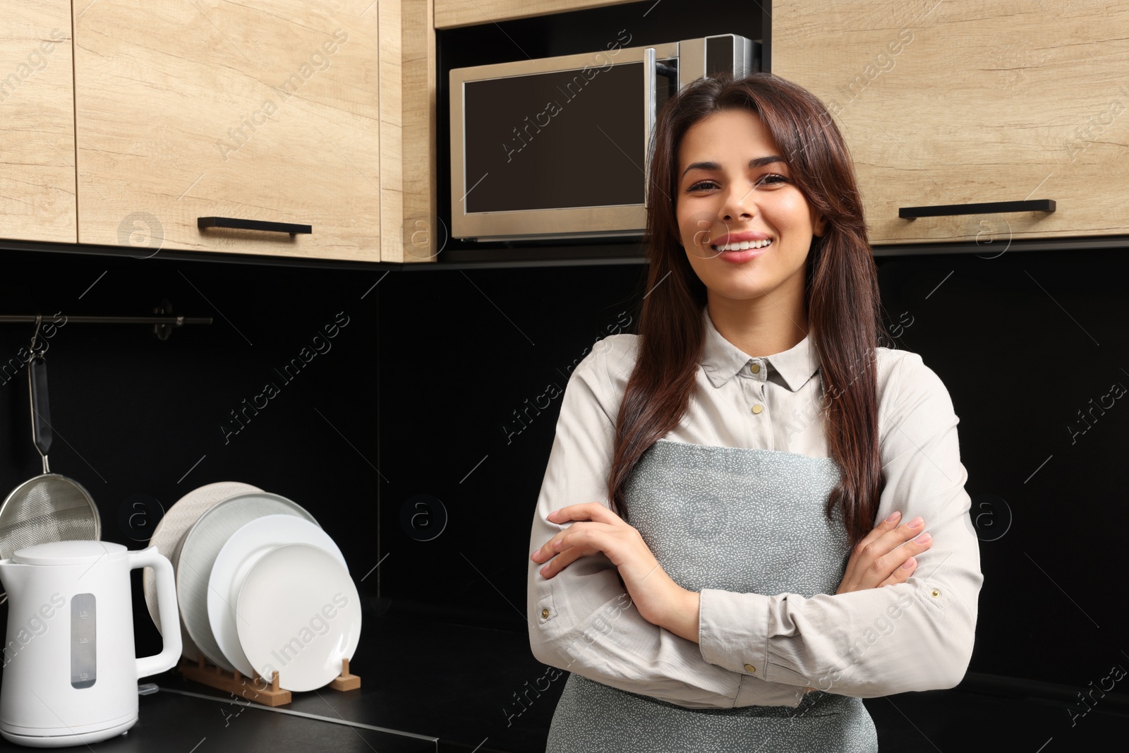 Photo of Young woman wearing green apron in kitchen, space for text