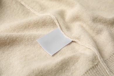 Photo of Warm beige cashmere sweater with clothing label, closeup