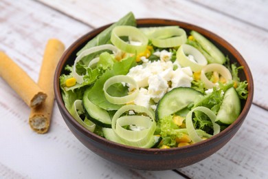 Bowl of tasty salad with leek, cheese and grissini on white wooden table, closeup