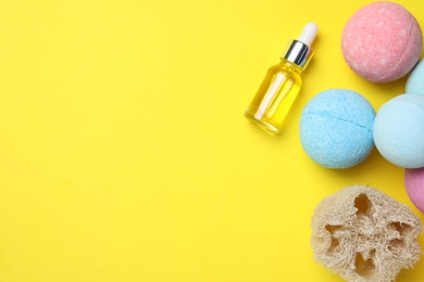 Bath bombs, loofah sponge and bottle on yellow background, flat lay. Space for text