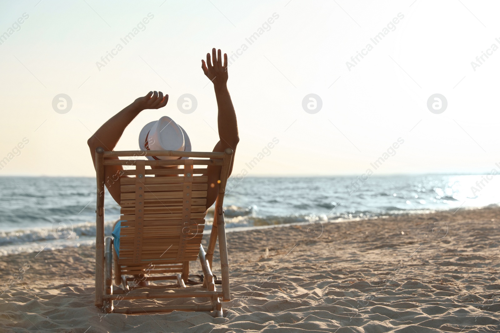 Photo of Young man relaxing in deck chair on beach near sea