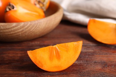 Photo of Piece of delicious ripe persimmon on wooden table, closeup