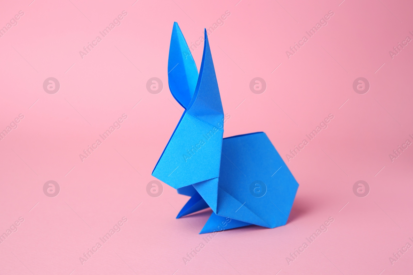 Photo of Origami art. Paper rabbit on pink background