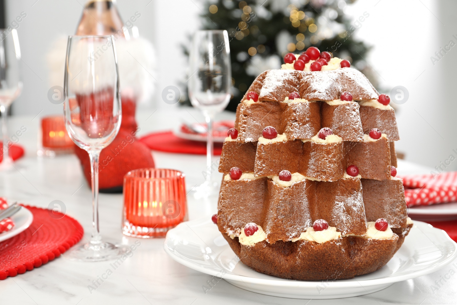 Photo of Delicious Pandoro Christmas tree cake decorated with powdered sugar and berries on white marble table