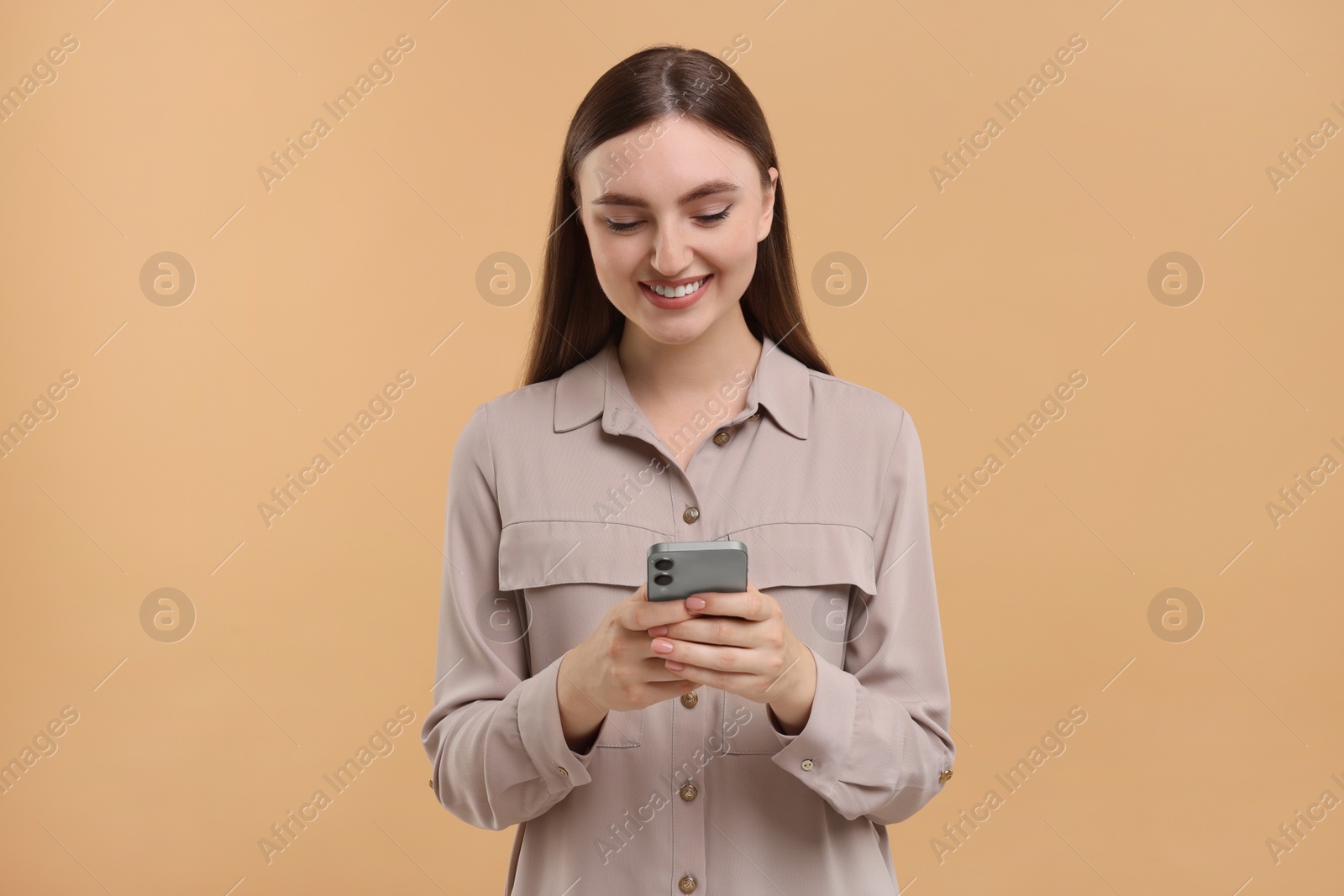 Photo of Smiling woman using smartphone on beige background