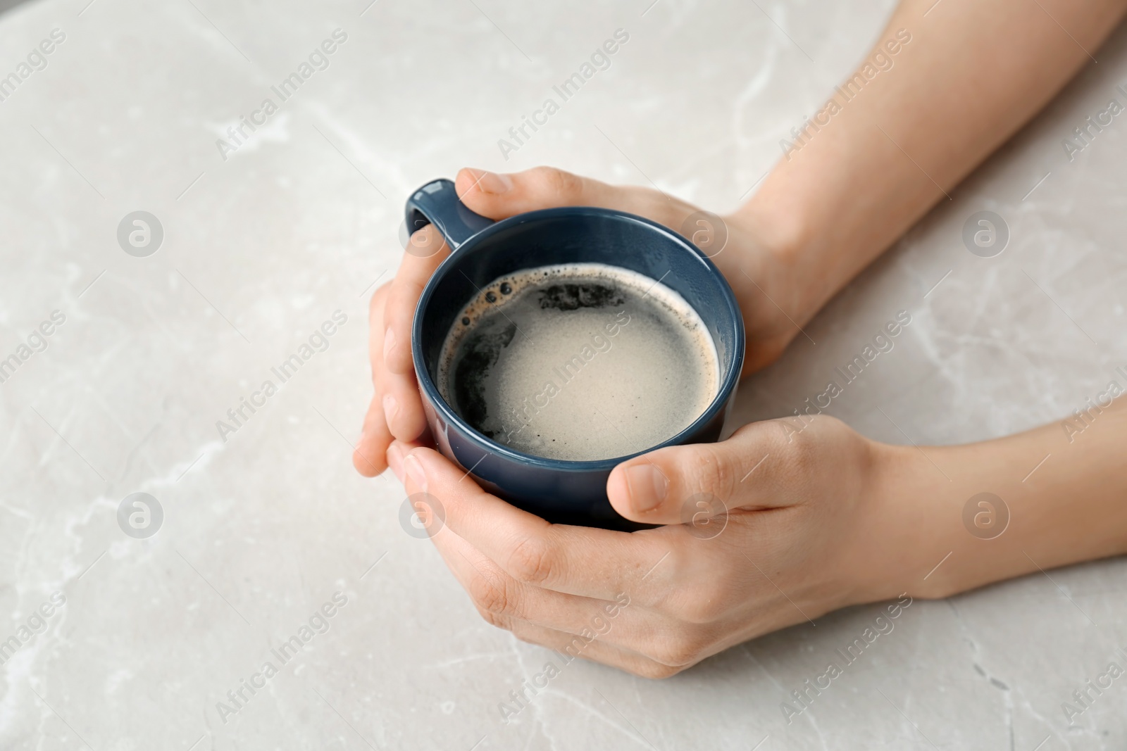 Photo of Young woman with cup of delicious hot coffee on light background