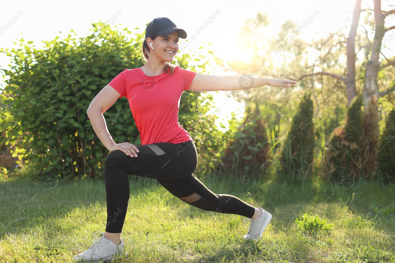 Photo of Young woman listening to music while doing morning exercise on green grass in park