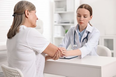 Photo of Arthritis symptoms. Doctor examining patient's elbow in hospital, selective focus