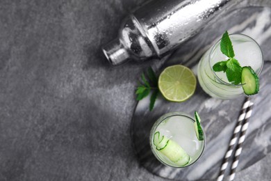 Photo of Glasses of refreshing cucumber water with ice on dark grey table, space for text