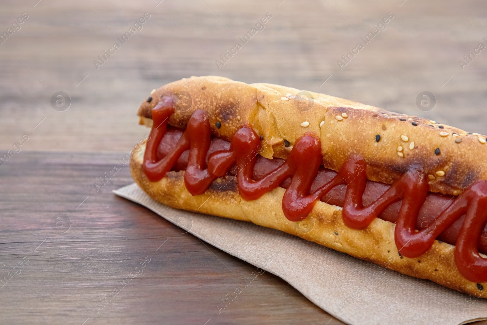 Photo of Fresh tasty hot dog with ketchup on wooden table, closeup