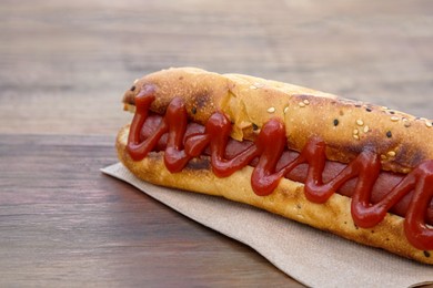 Photo of Fresh tasty hot dog with ketchup on wooden table, closeup