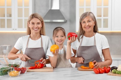 Photo of Three generations. Happy grandmother, her daughter and granddaughter cooking together in kitchen