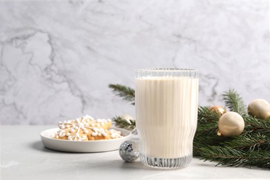 Photo of Glass of delicious eggnog and fir branch on light table, space for text