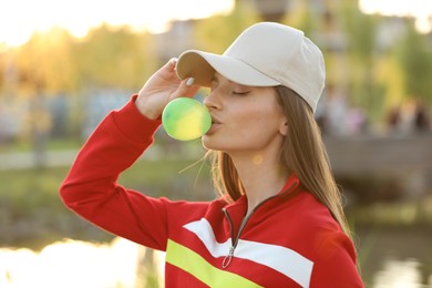 Photo of Beautiful young woman blowing bubble gum outdoors