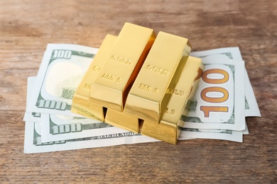 Photo of Gold bars and dollar bills on wooden table
