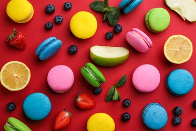 Photo of Flat lay composition with colorful macarons and ingredients on red background
