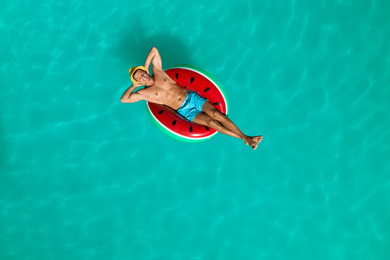 Happy man with inflatable ring in swimming pool, top view. Summer vacation