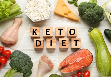 Photo of Cubes with phrase Keto Diet and different fresh products on white wooden table, flat lay
