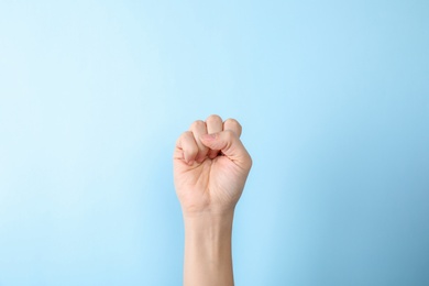 Woman showing S letter on color background, closeup. Sign language