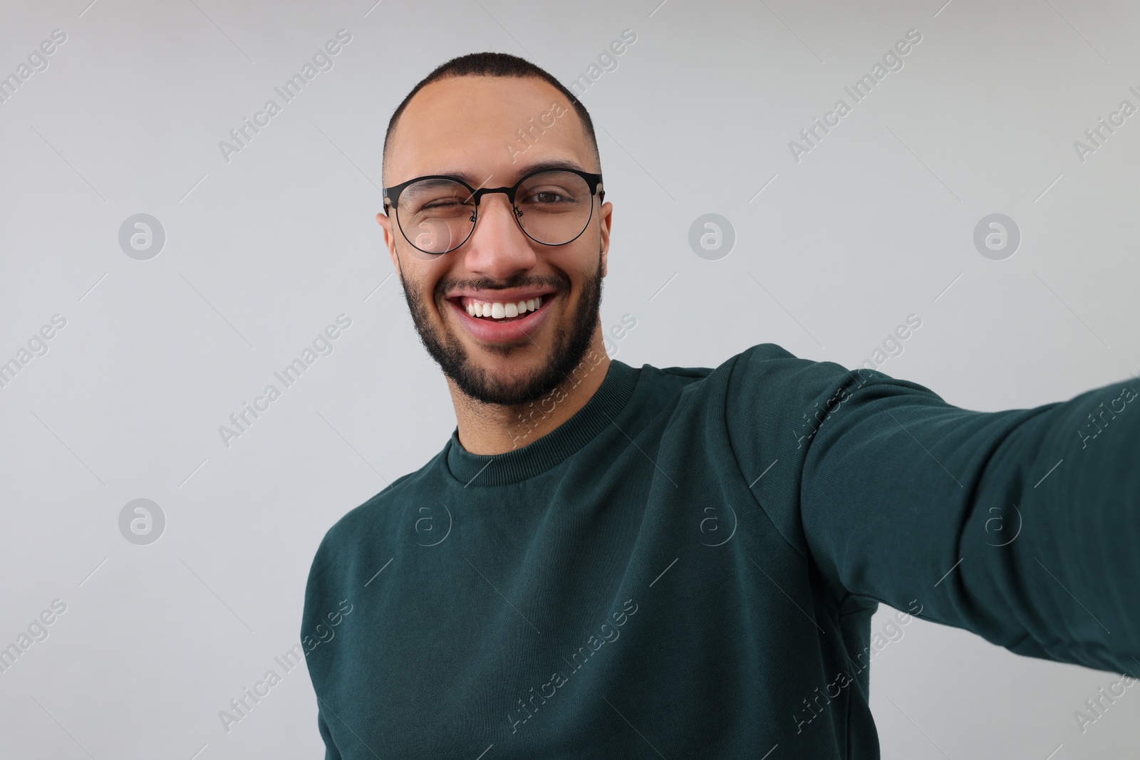 Photo of Smiling young man taking selfie on grey background