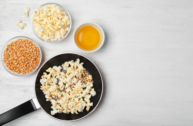 Composition with popcorn, oil and space for text on wooden table, flat lay