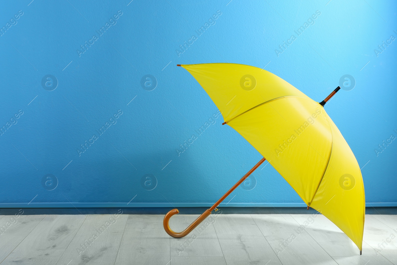 Photo of Beautiful yellow umbrella near blue wall. Space for text