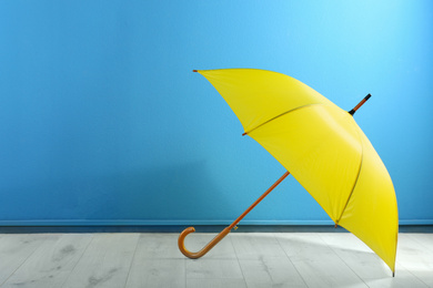 Photo of Beautiful yellow umbrella near blue wall. Space for text