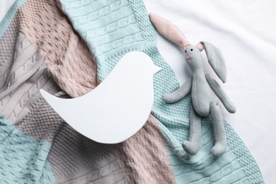 Photo of Bird shaped child's night lamp and toy bunny on color fabric, flat lay