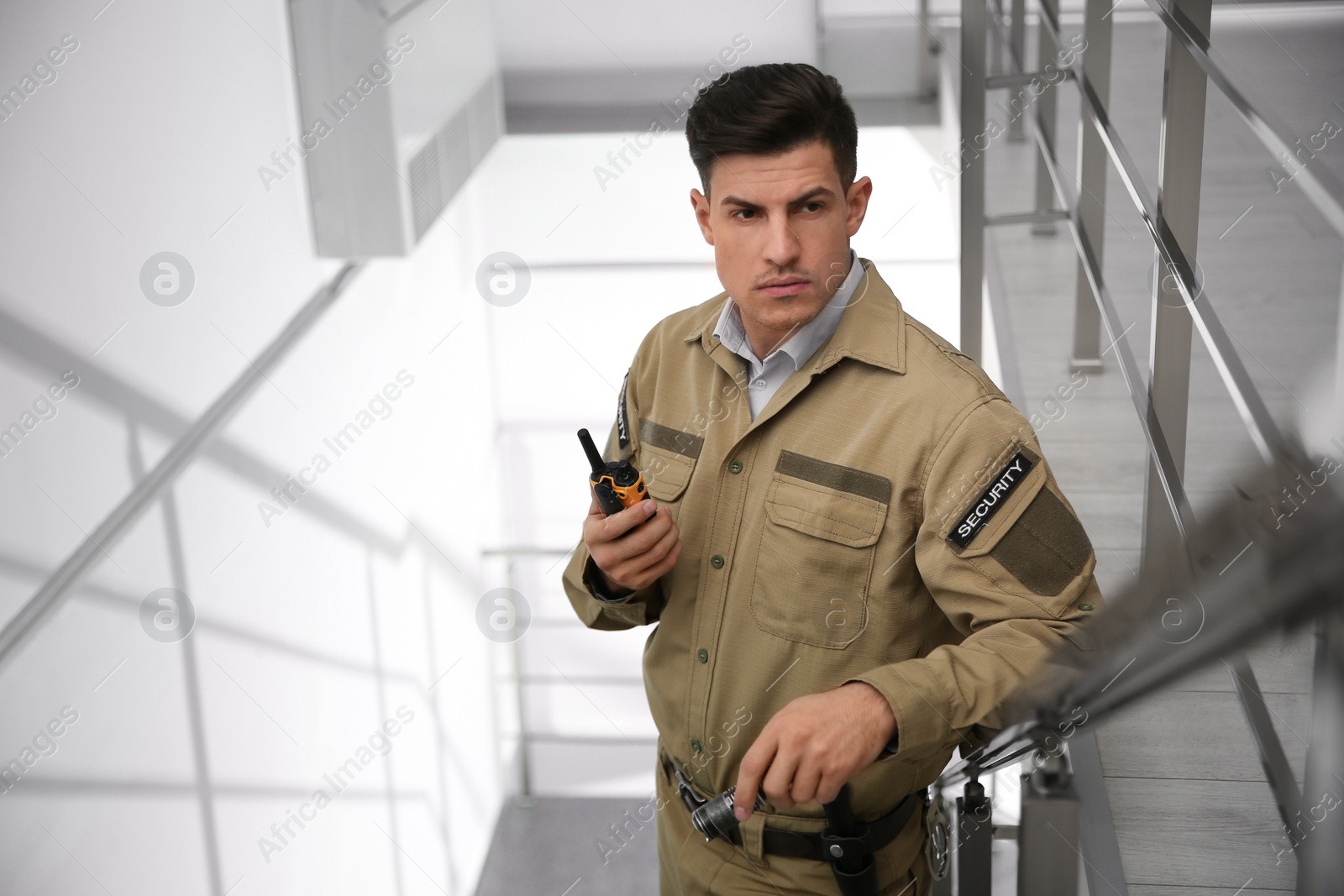 Photo of Professional security guard with portable radio set on stairs