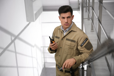 Photo of Professional security guard with portable radio set on stairs