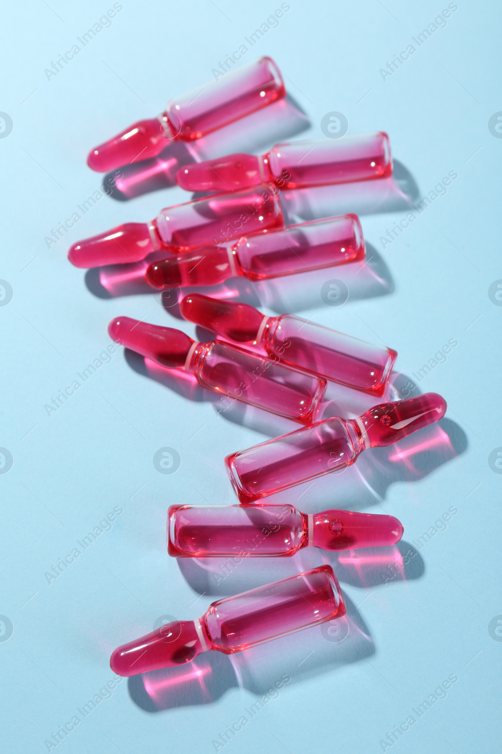 Photo of Glass ampoules with liquid on light blue background, above view