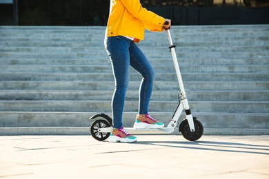 Woman riding electric kick scooter outdoors on sunny day