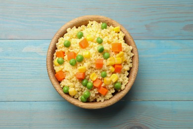 Photo of Tasty millet porridge with vegetables in bowl on light blue wooden table, top view