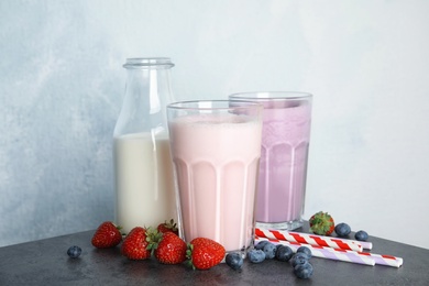 Delicious milk shakes and ingredients on table against light background