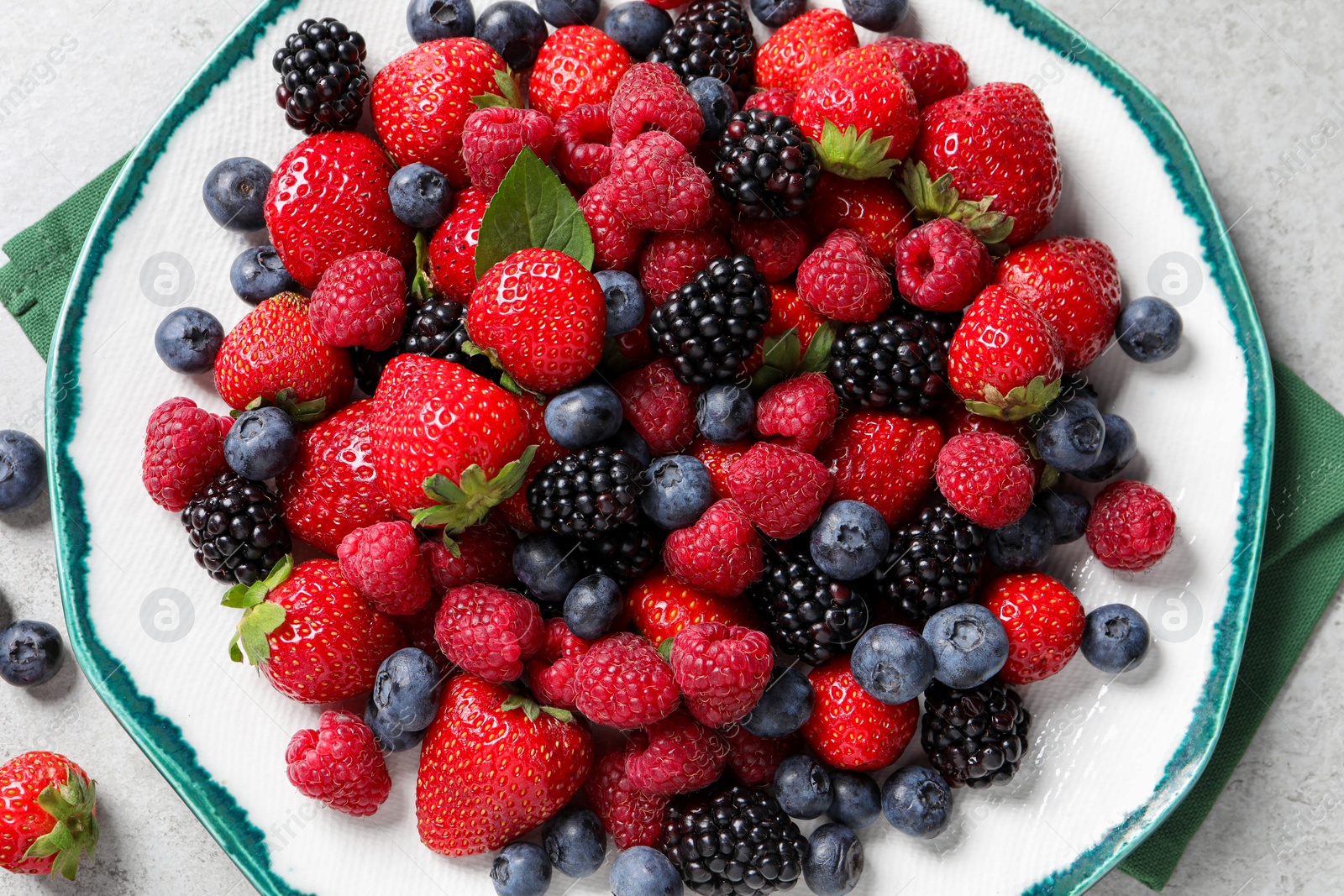 Different fresh ripe berries on light grey table, top view Photo of Different fresh ripe berries on light grey table, top view