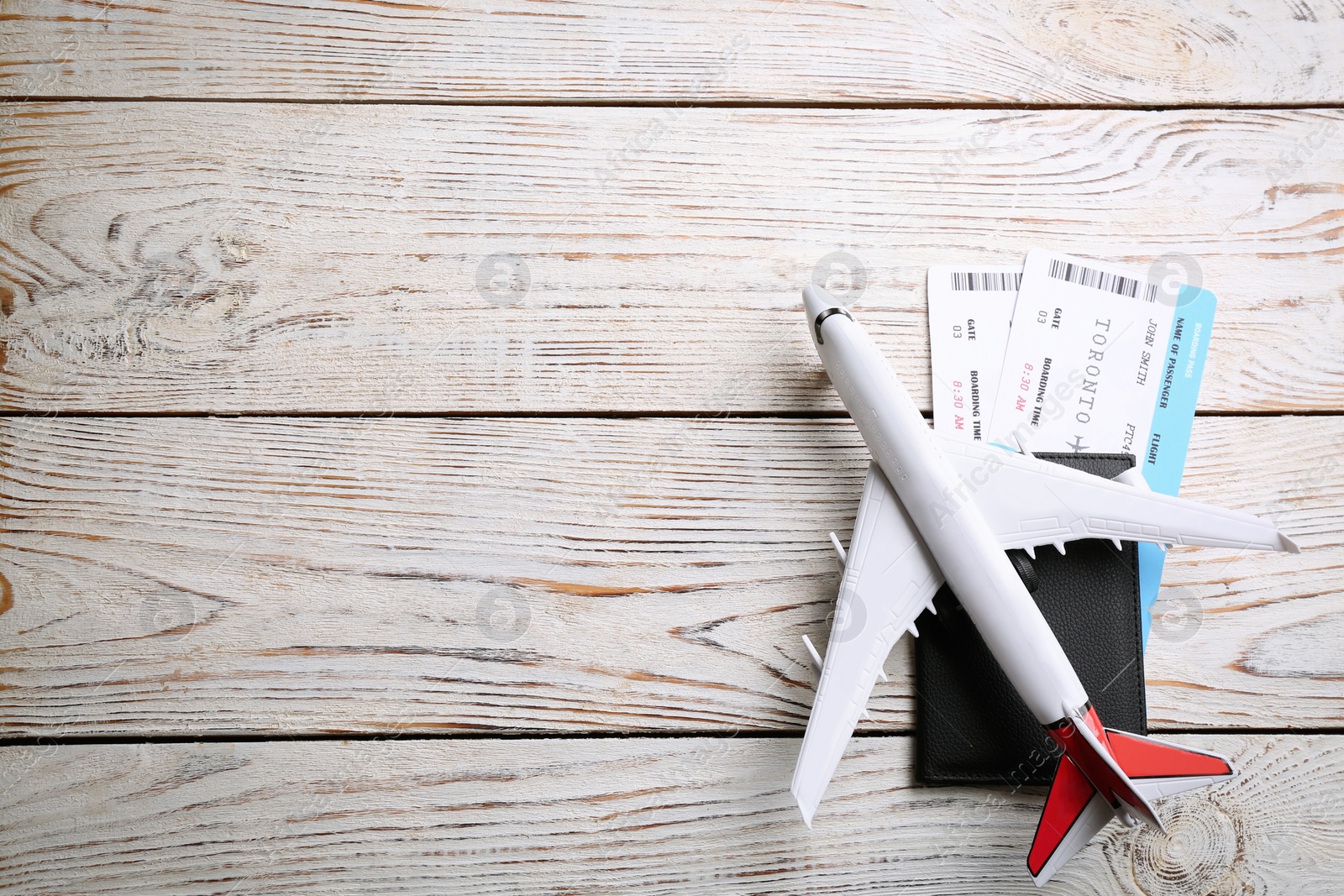 Photo of Toy airplane and passport with tickets on white wooden background, flat lay. Space for text