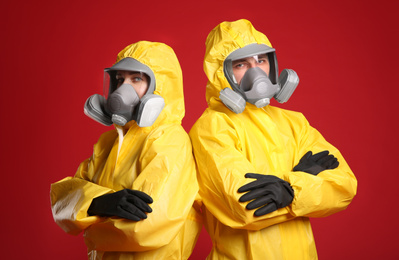 Photo of Man and woman wearing chemical protective suits on red background. Virus research