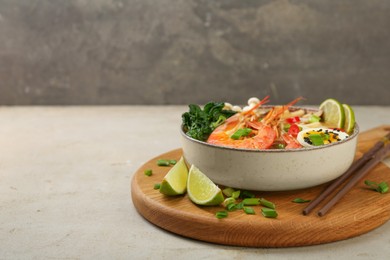 Delicious ramen with shrimps, egg in bowl and chopsticks on light textured table, space for text. Noodle soup